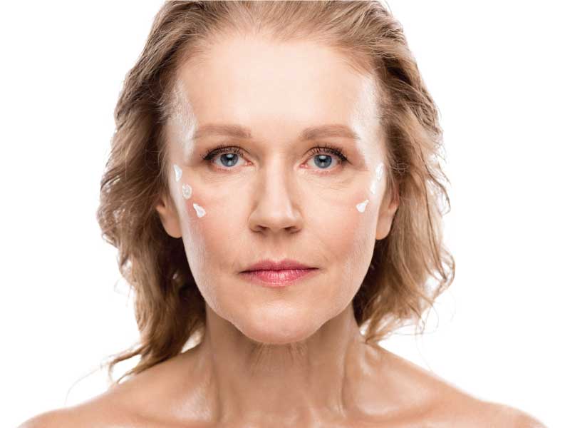 mature woman with cosmetic Anti Ageing cream on face looking